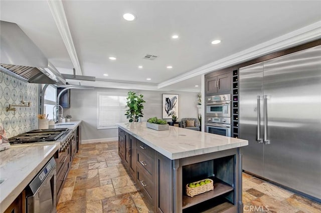 kitchen featuring open shelves, a sink, stone tile floors, stainless steel appliances, and wall chimney range hood