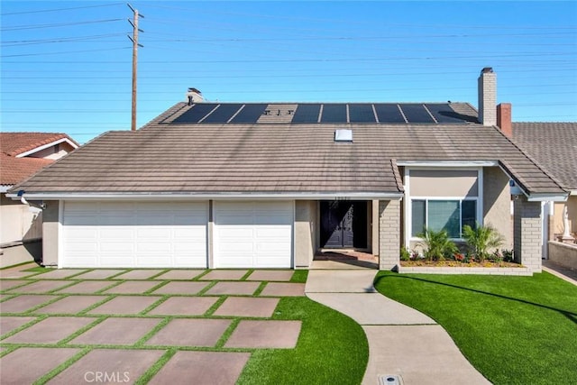 view of front facade featuring stucco siding, a front lawn, a tile roof, a garage, and solar panels