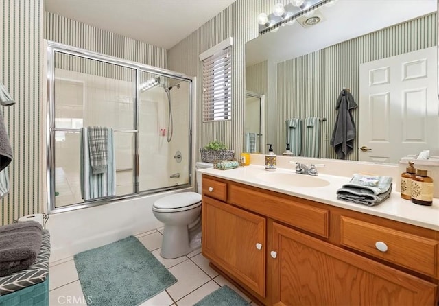 full bathroom featuring bath / shower combo with glass door, toilet, vanity, tile patterned flooring, and wallpapered walls