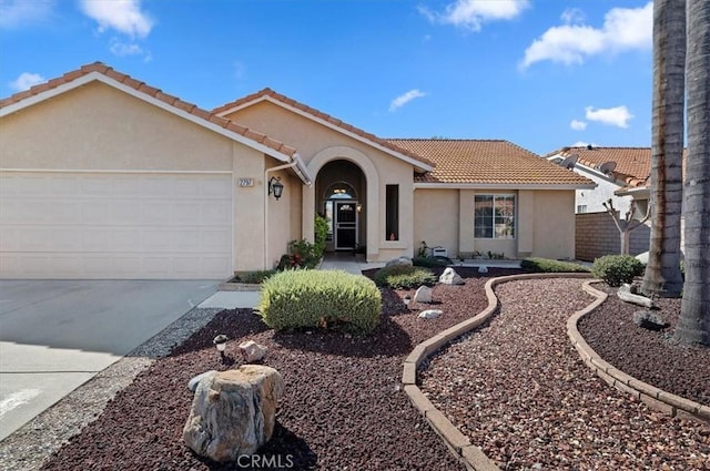 ranch-style home with concrete driveway, a tiled roof, an attached garage, and stucco siding