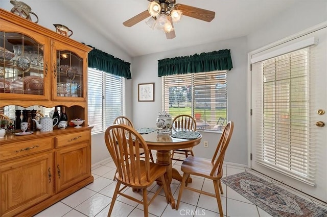 dining space with ceiling fan, vaulted ceiling, baseboards, and light tile patterned floors