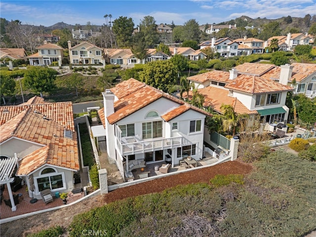 rear view of house with a balcony, a residential view, a chimney, a patio area, and a mountain view