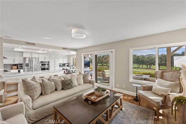 living area with visible vents, plenty of natural light, and wood finished floors