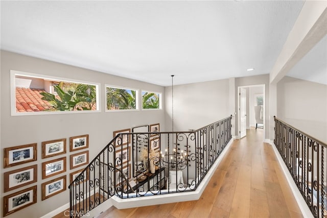 hall featuring recessed lighting, an inviting chandelier, an upstairs landing, wood finished floors, and baseboards