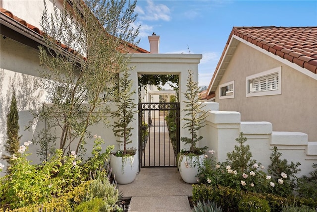 doorway to property featuring stucco siding, a gate, and a tiled roof