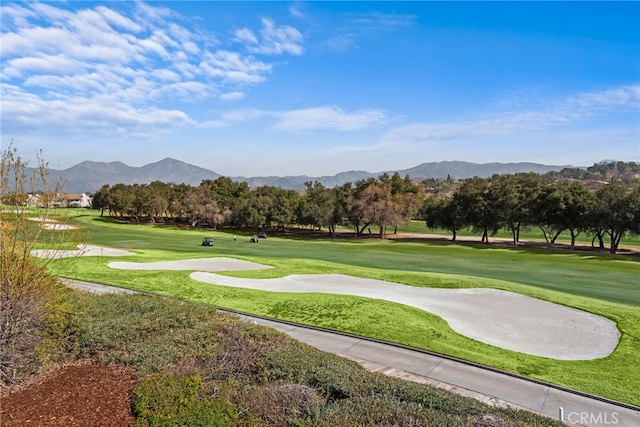 view of community featuring view of golf course, a mountain view, and a yard