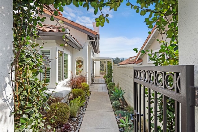 view of side of property featuring stucco siding, a gate, and a tiled roof