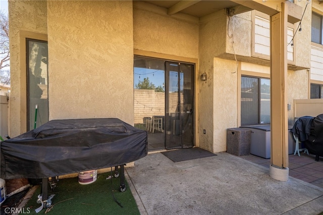 view of exterior entry featuring a patio, fence, and stucco siding