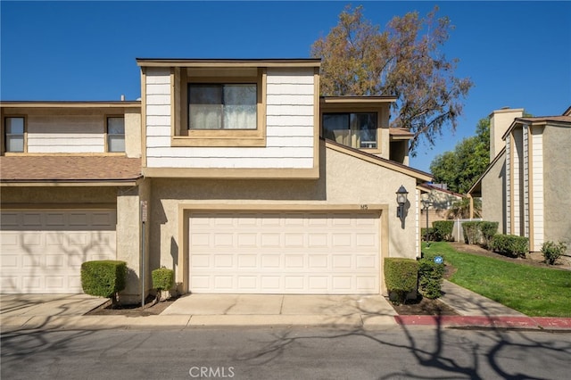 view of property with a garage, concrete driveway, and stucco siding