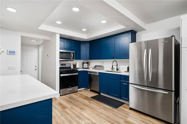 kitchen featuring blue cabinetry, appliances with stainless steel finishes, light countertops, and a sink