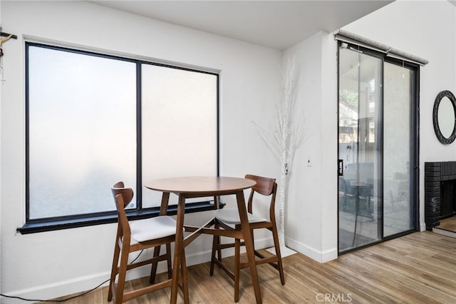 dining room with light wood finished floors, plenty of natural light, and baseboards