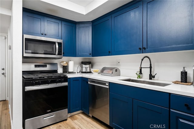 kitchen featuring light countertops, appliances with stainless steel finishes, blue cabinetry, and a sink