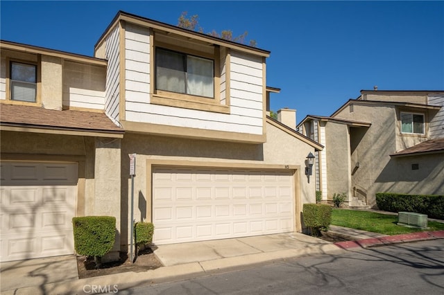 view of property featuring an attached garage, driveway, cooling unit, and stucco siding