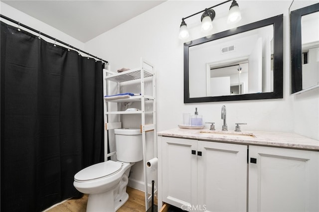 bathroom featuring visible vents, vanity, toilet, and wood finished floors