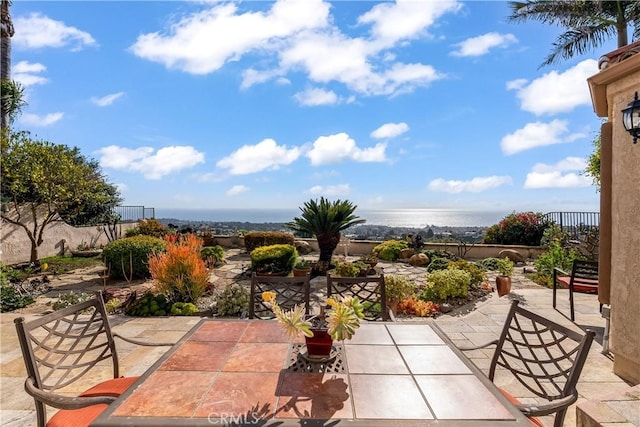 view of patio with a water view and fence