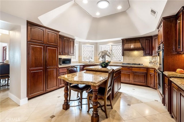 kitchen featuring custom range hood, stainless steel microwave, a sink, gas stovetop, and backsplash