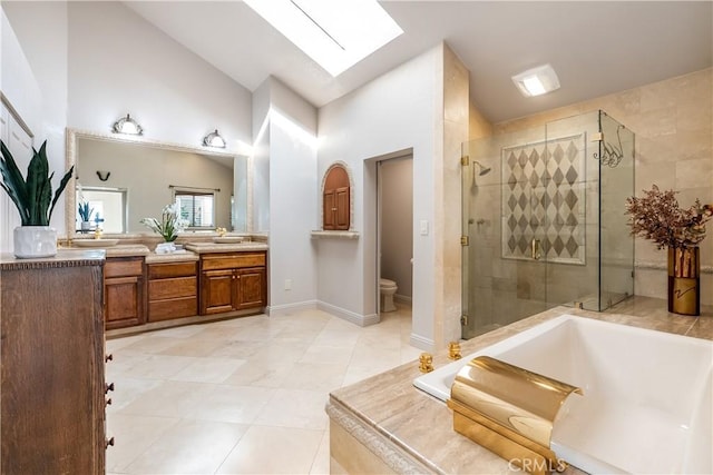 full bath with double vanity, a skylight, a stall shower, toilet, and a bath