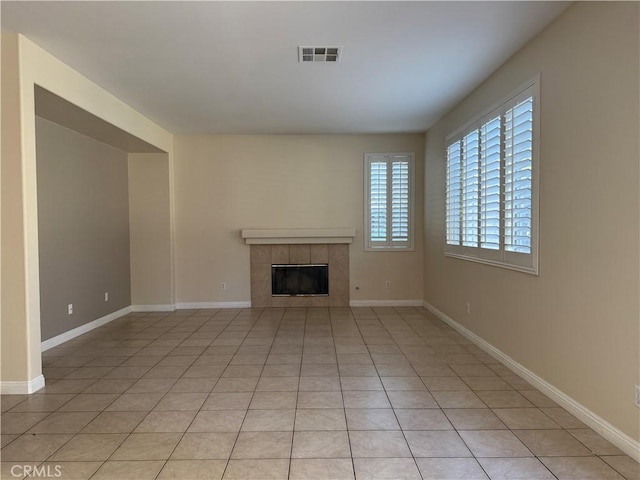 unfurnished living room with baseboards, visible vents, a tiled fireplace, and light tile patterned floors