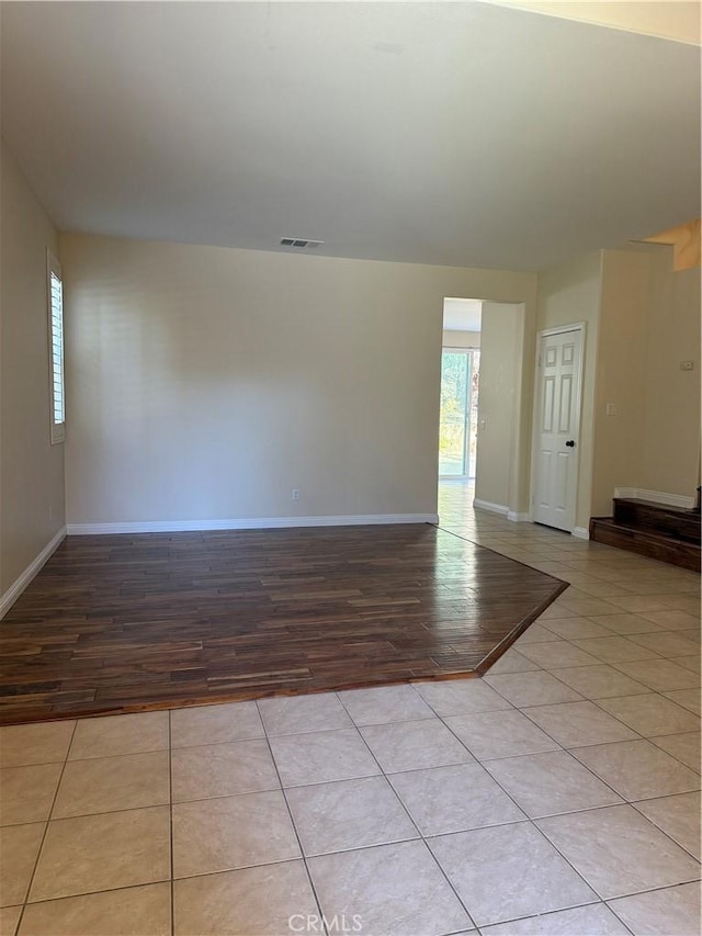 empty room featuring light tile patterned floors, plenty of natural light, visible vents, and baseboards