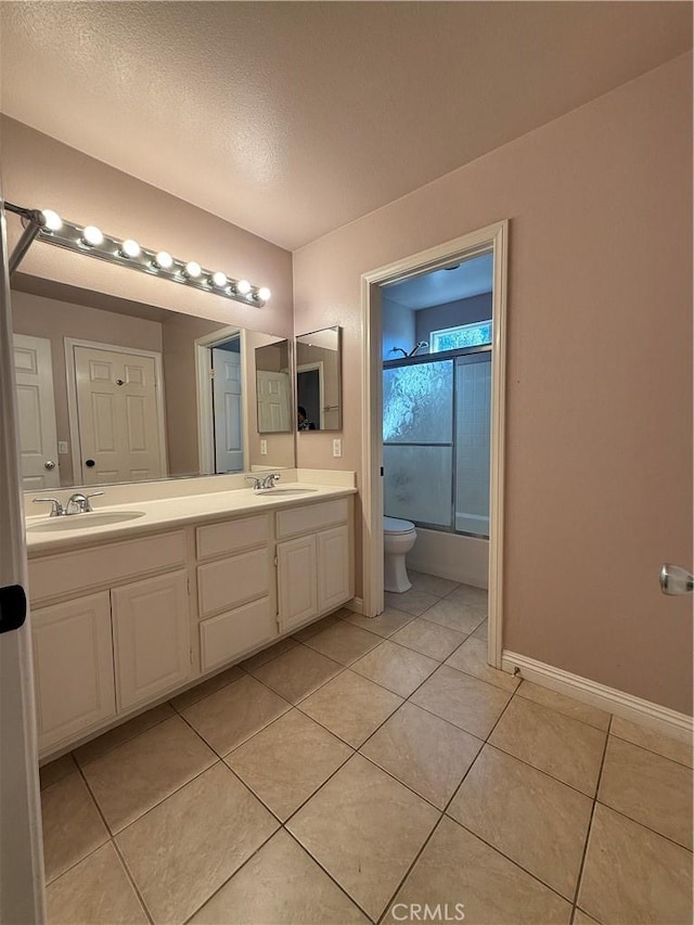 full bath featuring enclosed tub / shower combo, double vanity, a sink, and tile patterned floors