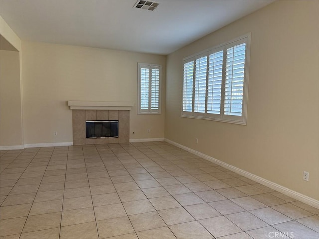 unfurnished living room with a tile fireplace, visible vents, and baseboards