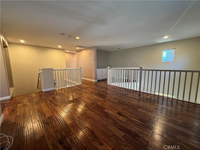 empty room featuring dark wood-type flooring, recessed lighting, visible vents, and baseboards