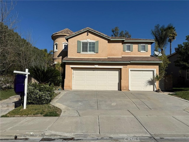 view of front of home with a garage, a tile roof, concrete driveway, and stucco siding