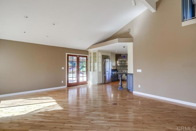 unfurnished living room with high vaulted ceiling, french doors, light wood-style flooring, and baseboards