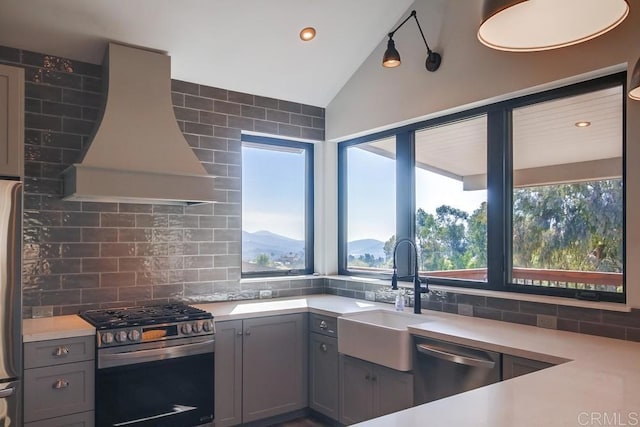 kitchen featuring gray cabinetry, stainless steel appliances, premium range hood, a sink, and light countertops