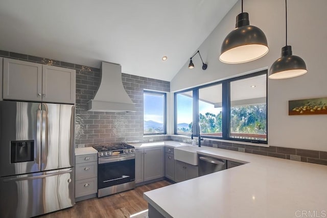 kitchen with light countertops, appliances with stainless steel finishes, hanging light fixtures, gray cabinets, and custom range hood