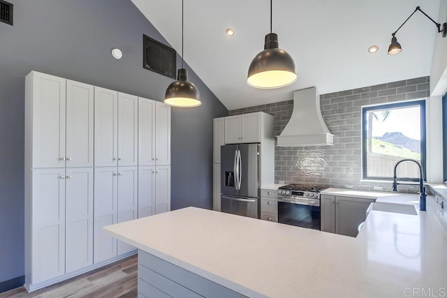 kitchen featuring pendant lighting, custom exhaust hood, stainless steel appliances, light countertops, and white cabinets