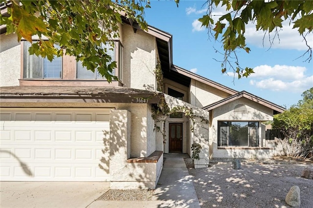 view of front facade featuring a garage, concrete driveway, and stucco siding