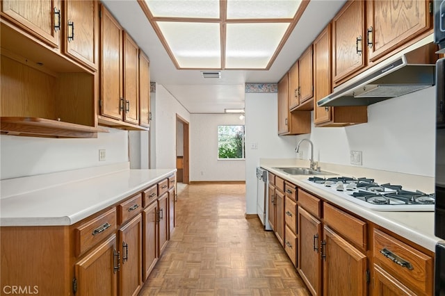 kitchen featuring white gas stovetop, brown cabinets, light countertops, stainless steel dishwasher, and a sink