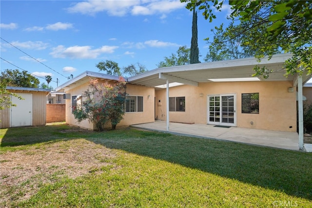 back of property with an outbuilding, stucco siding, a lawn, and a storage unit