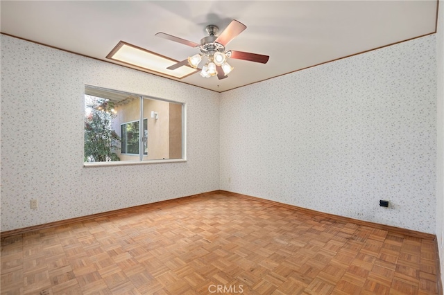 empty room featuring baseboards, ceiling fan, parquet floors, and wallpapered walls