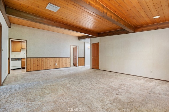 unfurnished room featuring visible vents, beamed ceiling, and light carpet