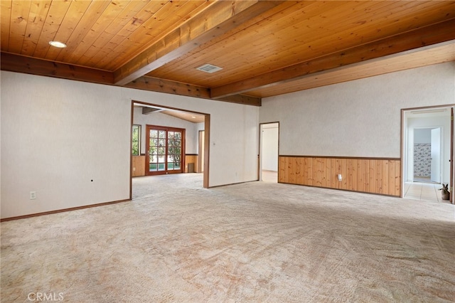 unfurnished room featuring wooden ceiling, light colored carpet, a wainscoted wall, visible vents, and beamed ceiling