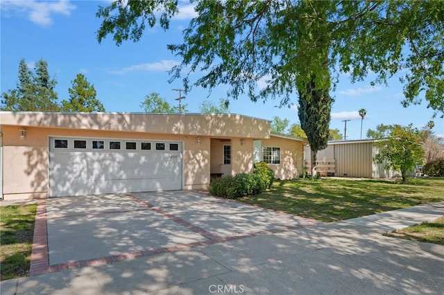 view of front of home with a garage, concrete driveway, a front lawn, and stucco siding