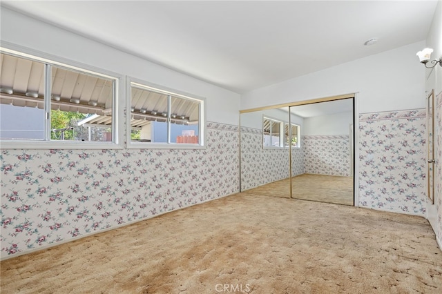 interior space featuring a closet, carpet, and wallpapered walls