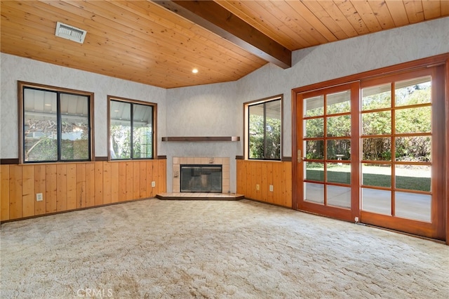 unfurnished living room featuring a fireplace, lofted ceiling with beams, wood ceiling, carpet flooring, and wood walls