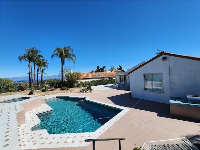 pool featuring a patio area, a hot tub, and an outdoor kitchen