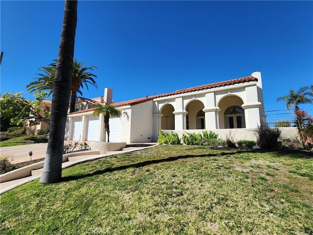 mediterranean / spanish home with a garage, stucco siding, and a front yard