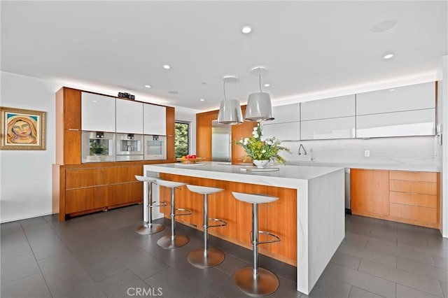 kitchen featuring modern cabinets, white cabinets, light countertops, and a kitchen breakfast bar