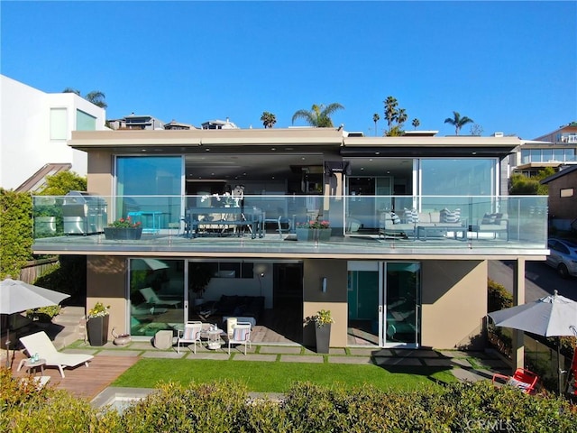 back of property with a balcony and stucco siding