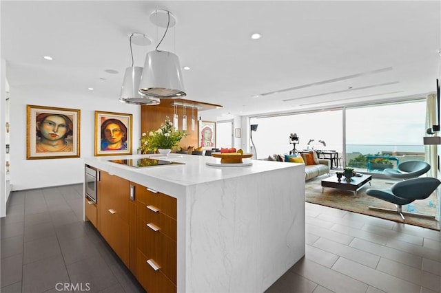 kitchen with a center island, light countertops, brown cabinetry, modern cabinets, and black electric cooktop