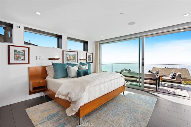 bedroom featuring recessed lighting, dark wood-type flooring, a water view, access to exterior, and a wall of windows