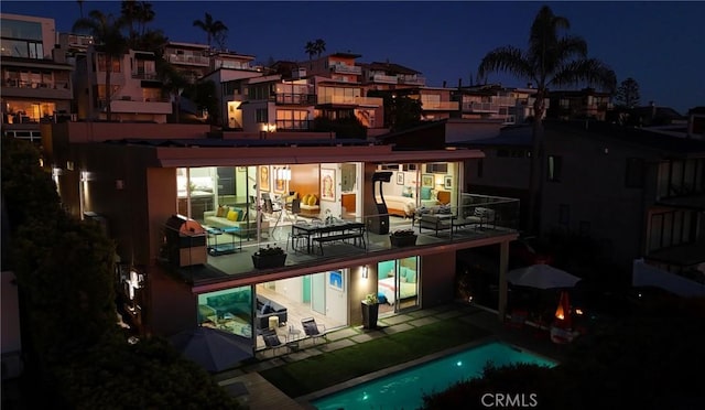 back of house at twilight featuring an outdoor pool