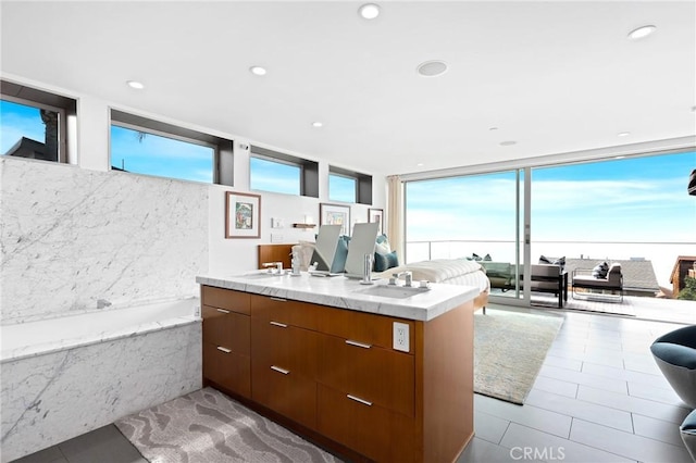 kitchen featuring a center island with sink, modern cabinets, expansive windows, light countertops, and a sink