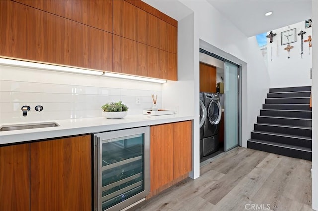 kitchen featuring modern cabinets, wine cooler, light countertops, and decorative backsplash