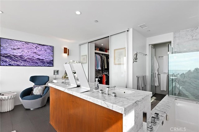 interior space featuring double vanity, a marble finish shower, a spacious closet, and visible vents